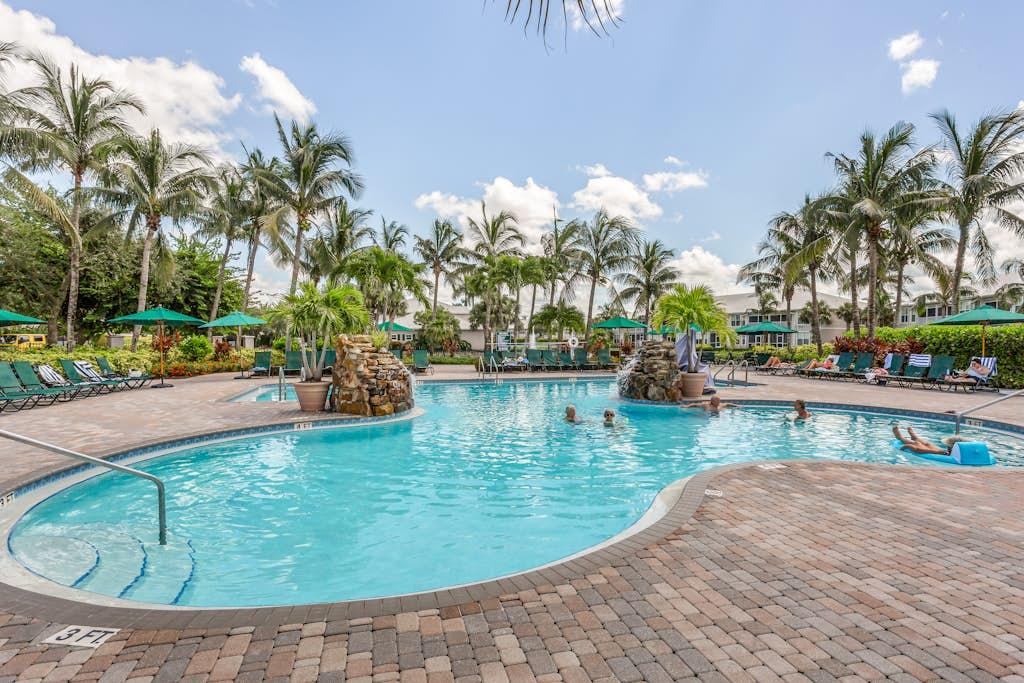 Resort-style community pool surrounded by palm trees at a VueStay Southwest Florida property